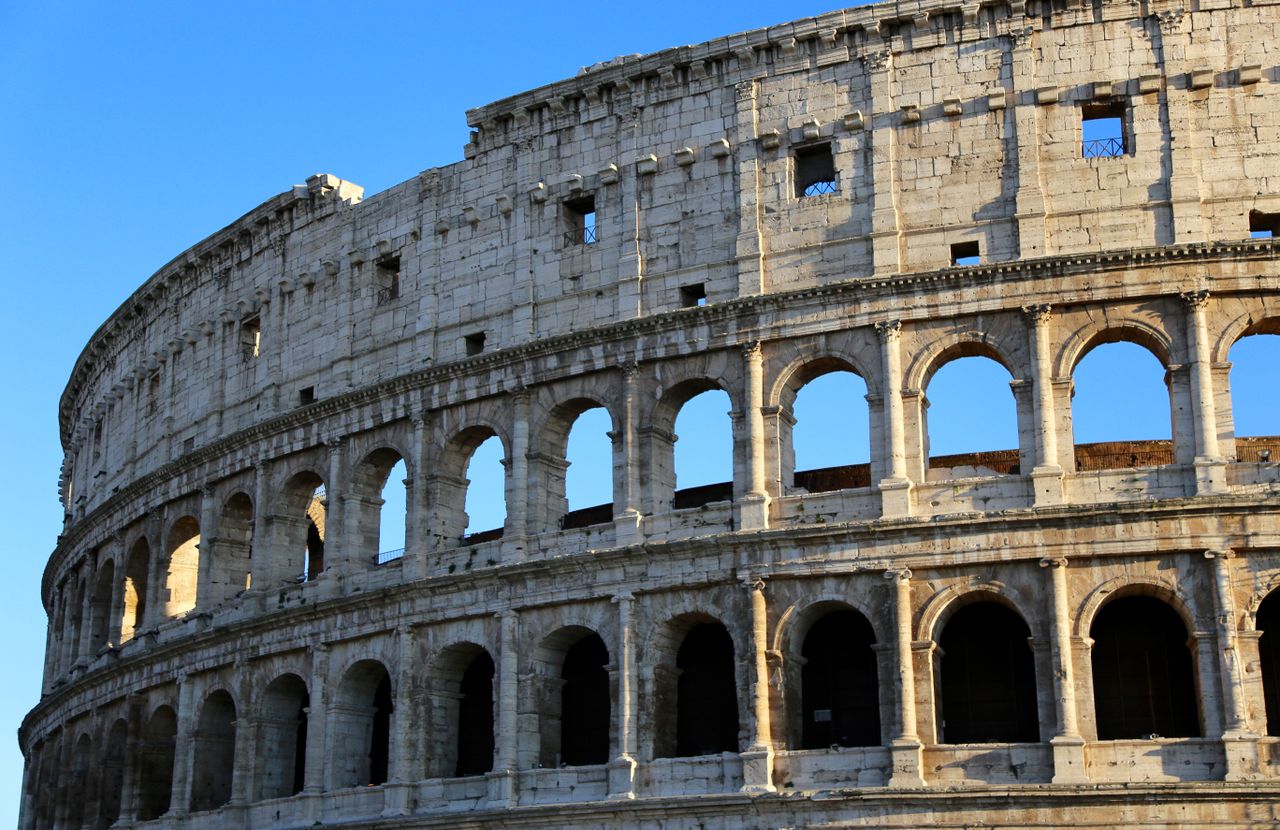 Close-up view of the iconic ancient Colosseum in Rome against a clear blue sky.