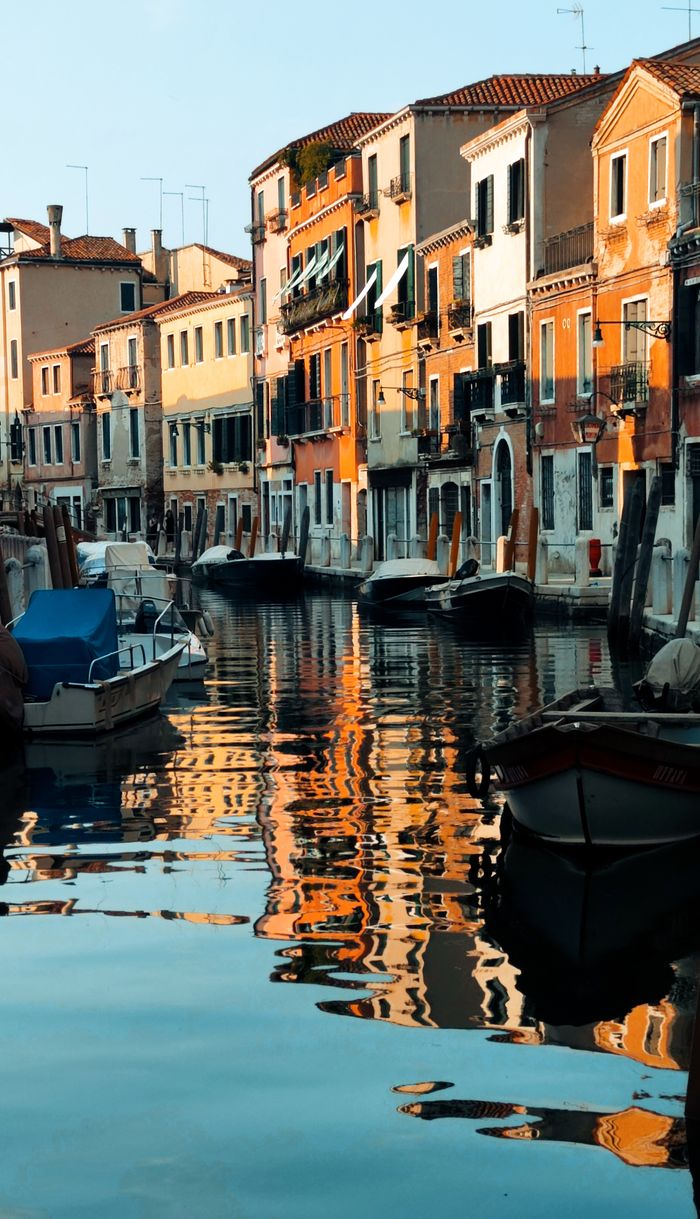 Vibrant canal scene featuring colorful buildings and moored boats in Venice, Italy.